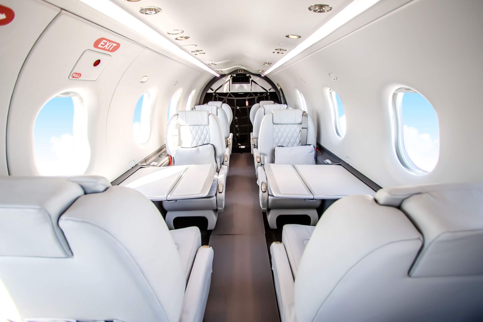PC-12 NG executive cabin with light gray leather club seating and foldout tables